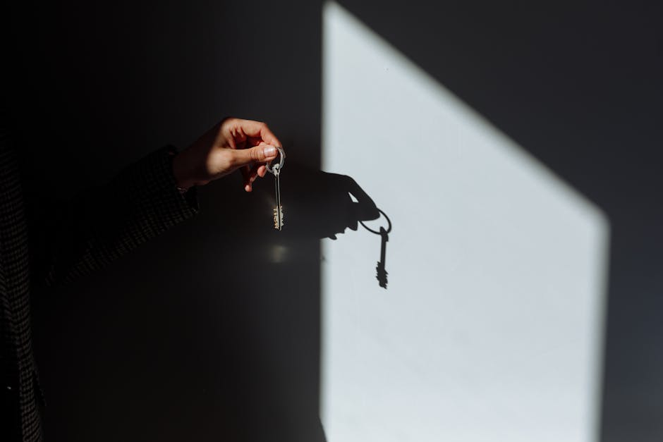 Minimalist photo of a hand holding a key casting a shadow, signifying property ownership